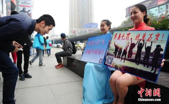 11月11日是“光棍节”，湖北武汉四名单身男女青年身穿旗袍和古装，手举“单身无罪，脱光万岁！”、“但愿人长久、光棍不再有”等字样的牌子奔走在武汉繁华的商业圈，希望通过这种方式摆脱单身，引发市民围观。中新社发 张畅 摄  