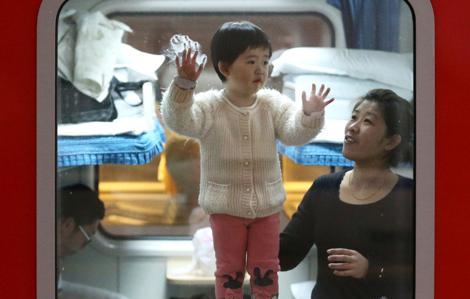 钱女士扶着自己的孩子在火车车窗边玩耍